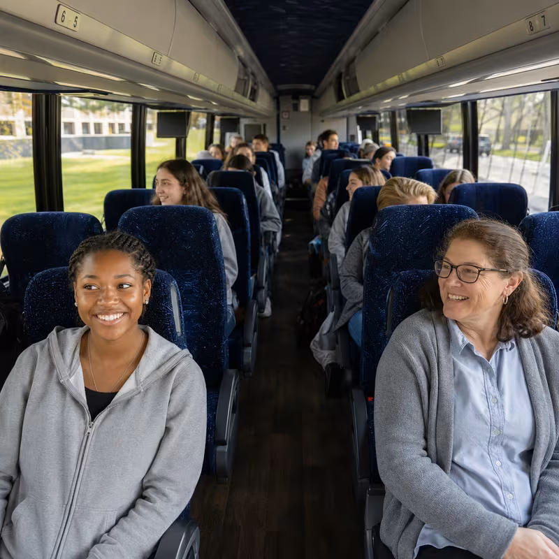 Group boarding a white charter bus for School Transportation transportation in Frederick